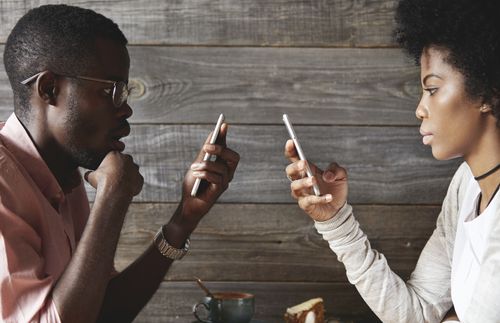 young couple looking at phones rather than each other