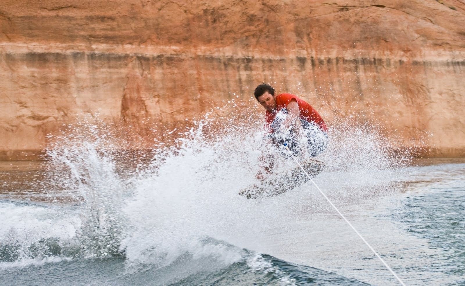 A young man jumps a wave on a wakeboard at Lake Powell.