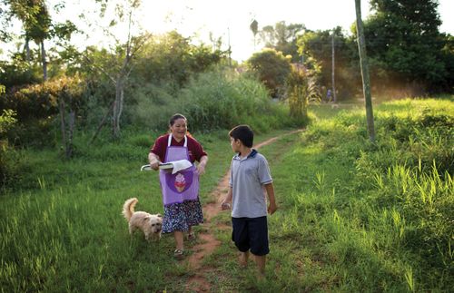 A woman with fresh baked bread is walking with her grandson.
