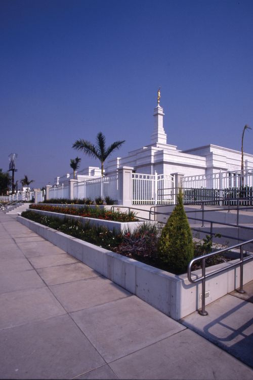 A view from afar of the Guadalajara Mexico Temple and grounds, with palm trees, plants, and flowers growing in abundance.