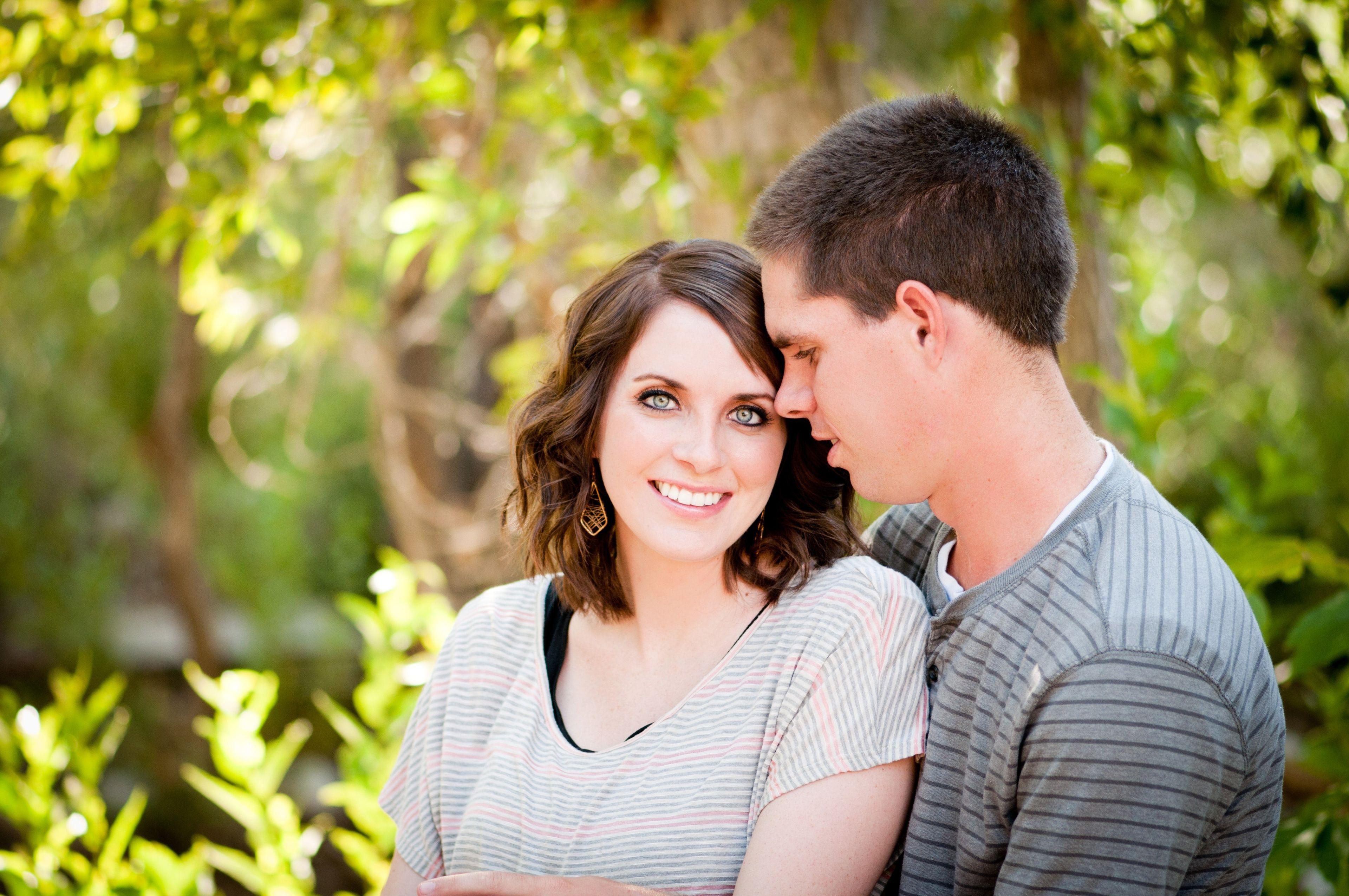 An engagement picture of a young couple outside.