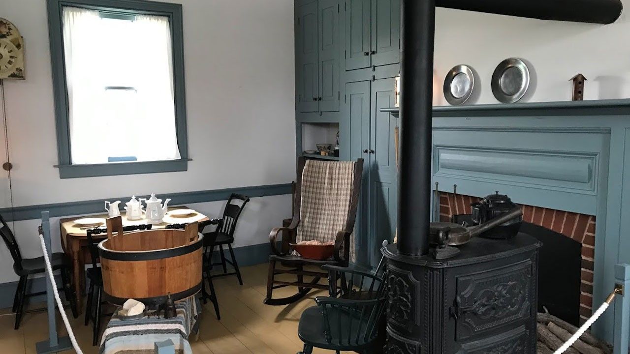 A living room with a fireplace, table and chairs. A window allows light into the room.