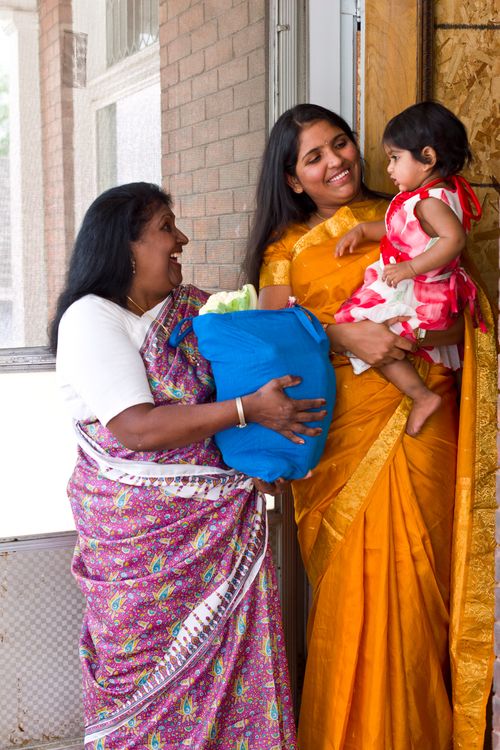 Two Indian woman talking together in the doorway of a home.
