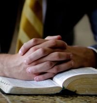 folded hands on scriptures