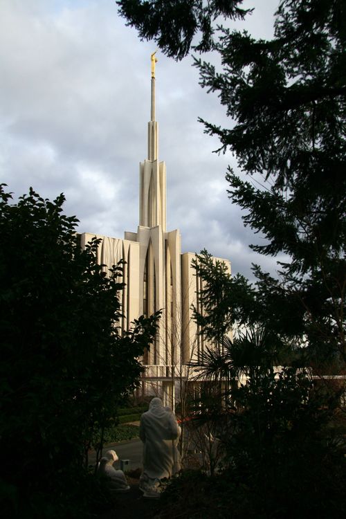 The Seattle Washington Temple, with a partial view of the front, framed by trees on the grounds of the temple.