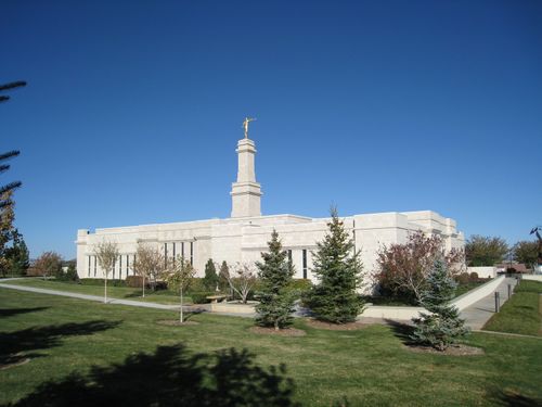 A full back view of the Monticello Utah Temple, surrounded by a walkway and green grass and trees.