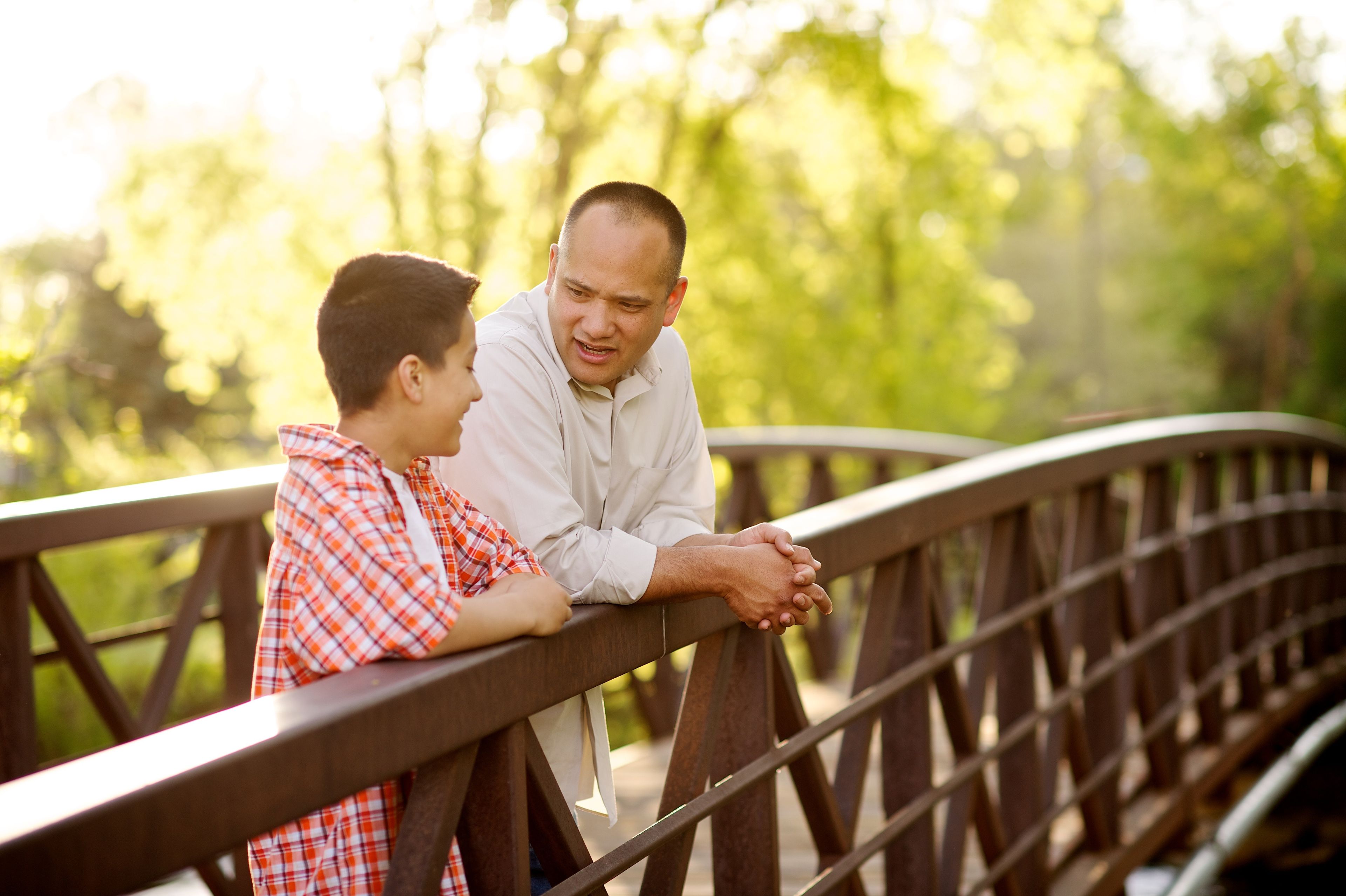 A father talks with his son on a bridge.