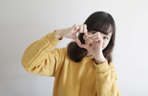 woman making a heart with her thumb and index fingers