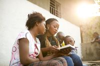 Mãe e filha sentadas juntas lendo as escrituras