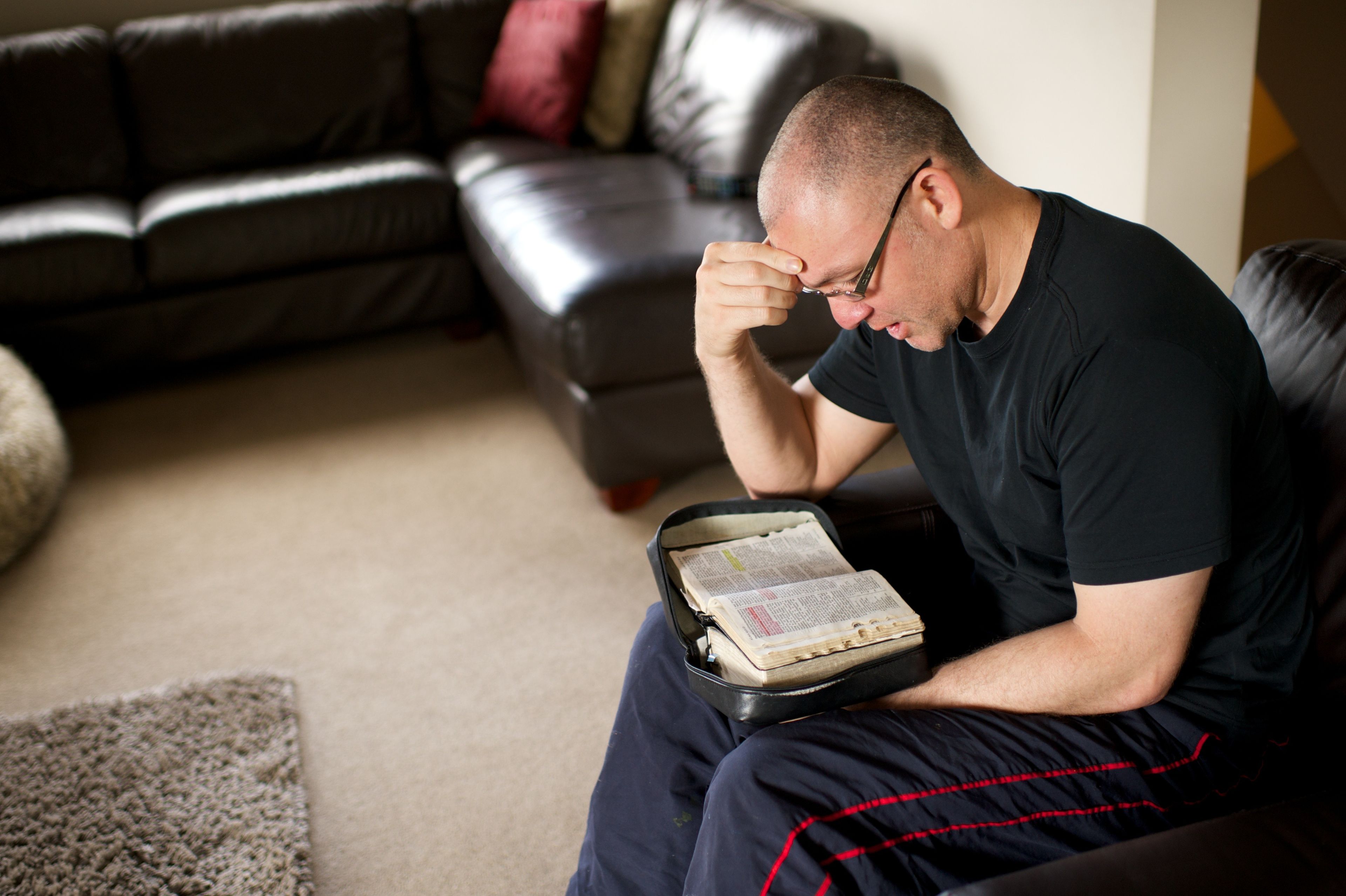 A man sits in his living room and studies the scriptures.