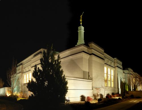 A side view of the Reno Nevada Temple lit up at night, with a partial view of the grounds.