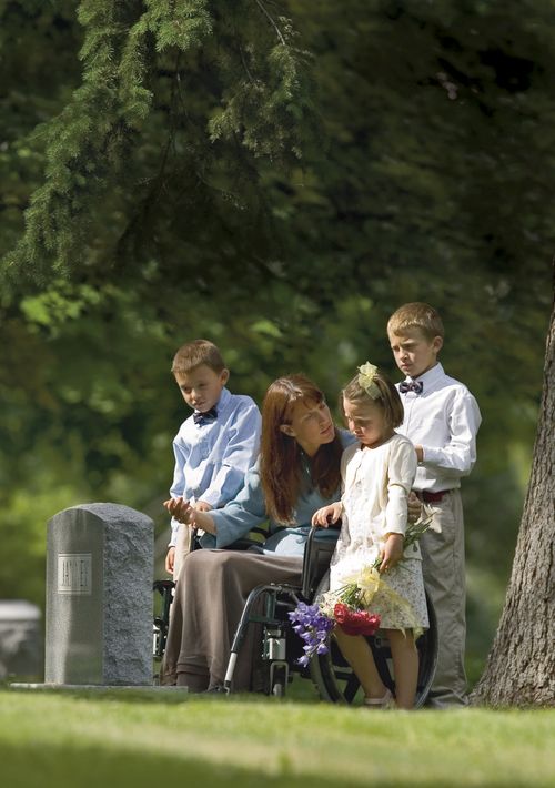 une mère et ses enfants près d’une tombe
