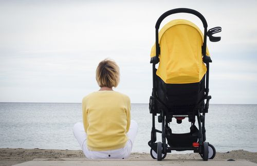 woman looking at the ocean while sitting with a stroller