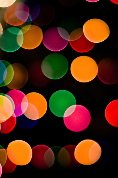 Green, yellow, pink, red, and blue circles of blurred light on a black background.
