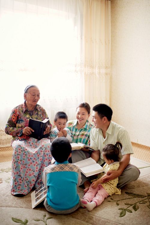 A family sits in a circle on the carpet and reads the scriptures together.