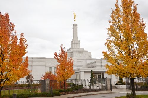 Trees with orange and yellow leaves outside the Spokane Washington Temple in the fall.