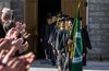 graduates walking, with girl in front carrying a flag