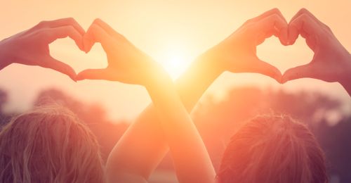 hands making heart symbols in the sun