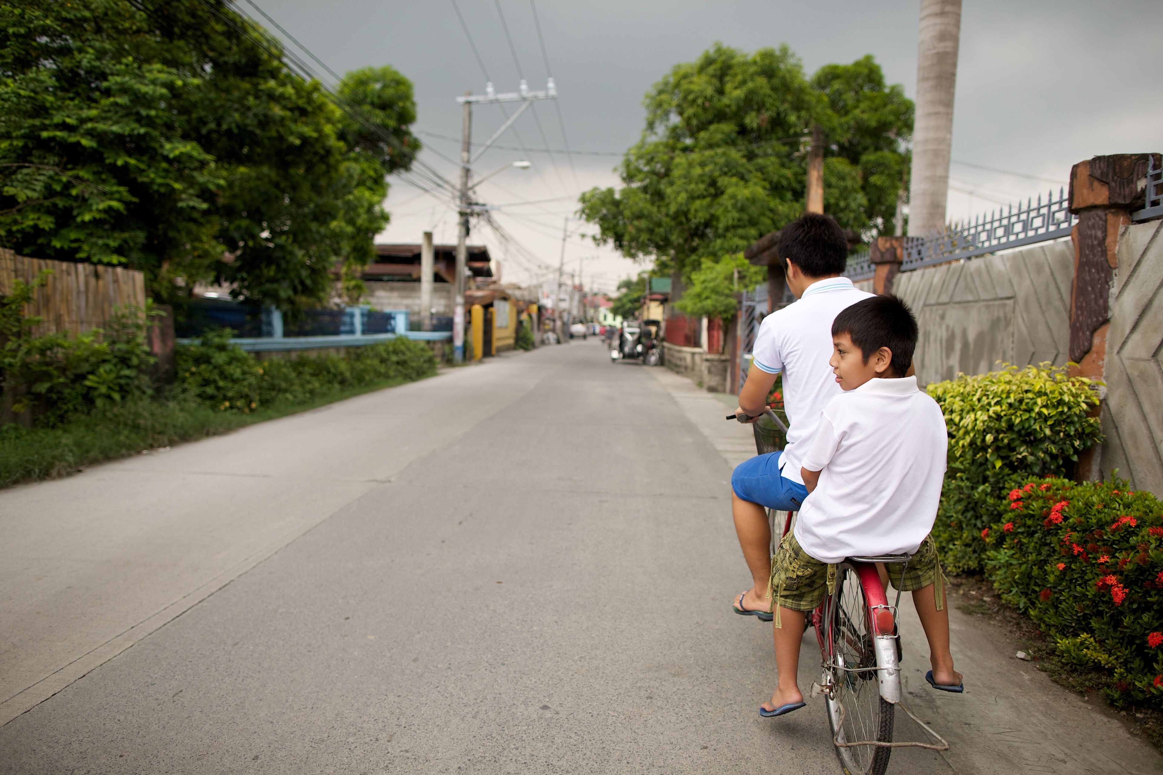 Two brothers from the Philippines ride a bike together.