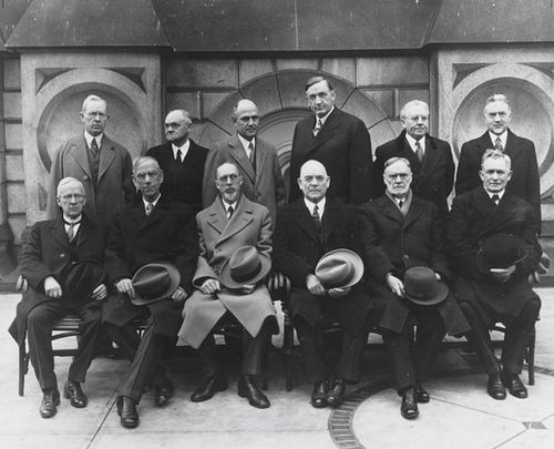 The Quorum of the Twelve Apostles in 1921, standing and seated in two rows: Joseph Fielding Smith, James E. Talmage, Stephen L Richards, Richard R. Lyman, Melvin J. Ballard, John A. Widtsoe, Rudger Clawson, Reed Smoot, George Albert Smith, George F. Richards, Orson F. Whitney, and David O. McKay.