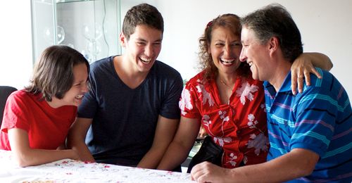 Family members sitting around a table.  They are talking to each other.