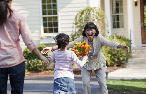 woman greeting child with flowers