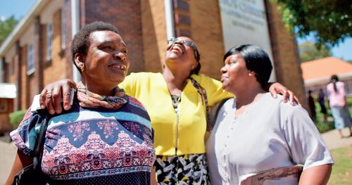 three women hugging and smiling