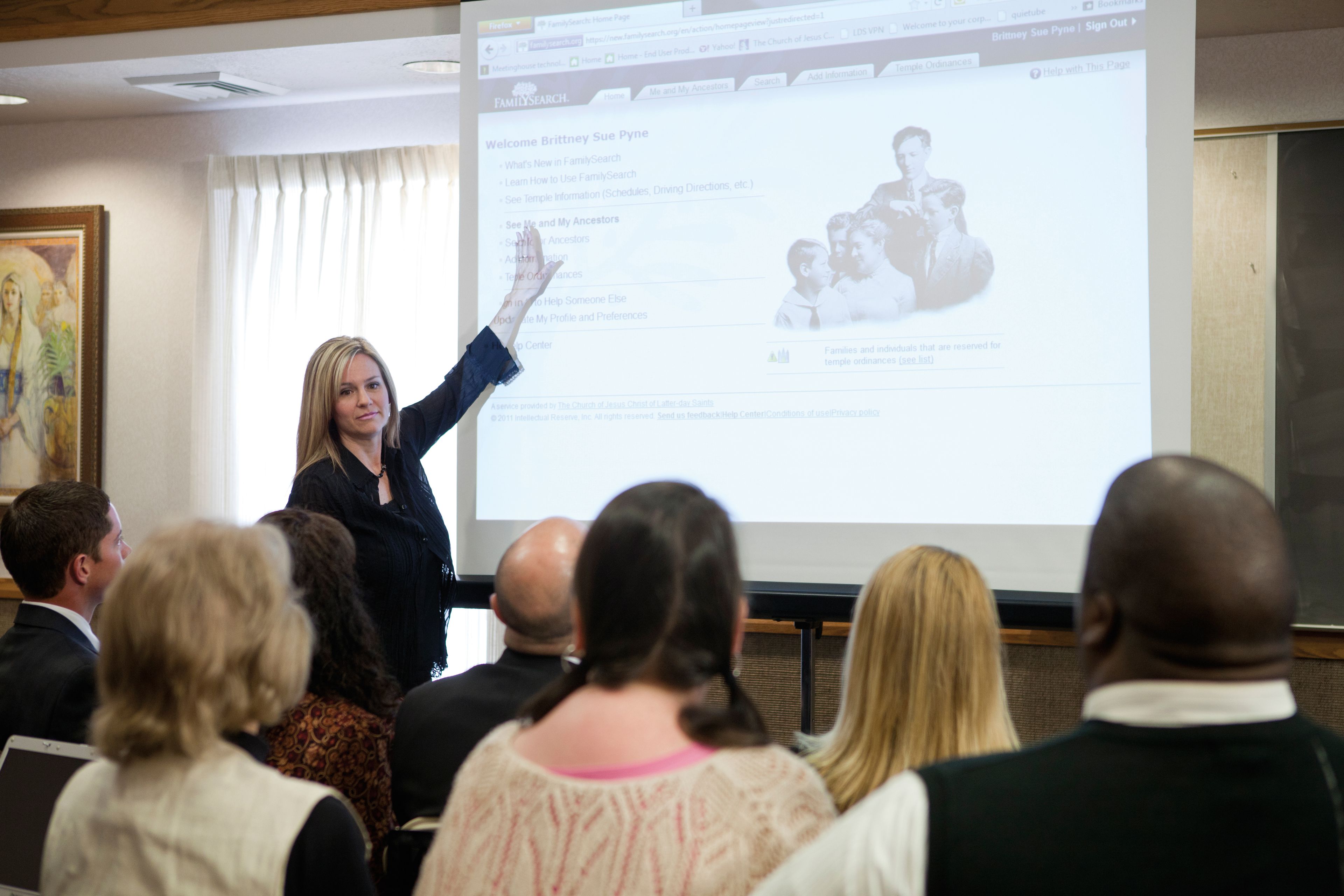 A Sunday School teacher projects her laptop display onto a screen to use for a lesson in a meetinghouse.