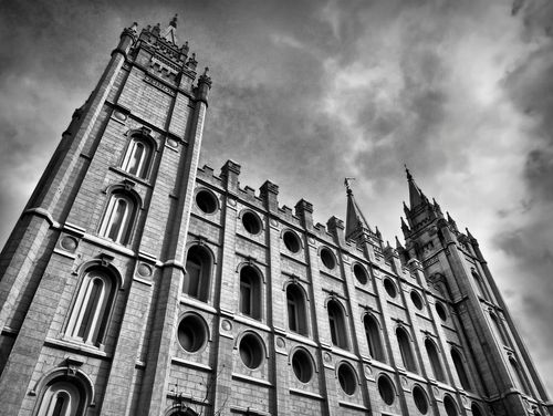 A black and white image of the Salt Lake Temple from the side, with a view of the windows and three spires.