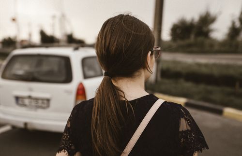 young adult woman by a car