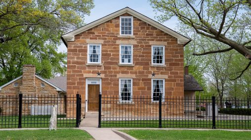 Front view of a two-story jail built from red limestone.