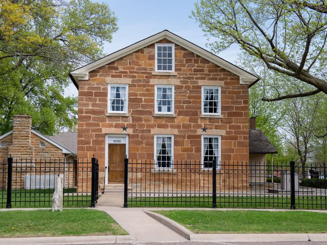 Front view of a two-story jail built from red limestone.