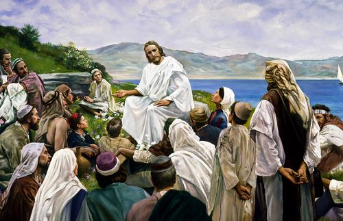 Jesus Christ sitting on a hillside preaching to a crowd of people. Mountains and sea are visible in the background. A reproduction by Grant Romney Clawson of the original “Sermon on the Mount” by Harry Anderson.