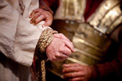 Un soldado romano ata las manos de Cristo.