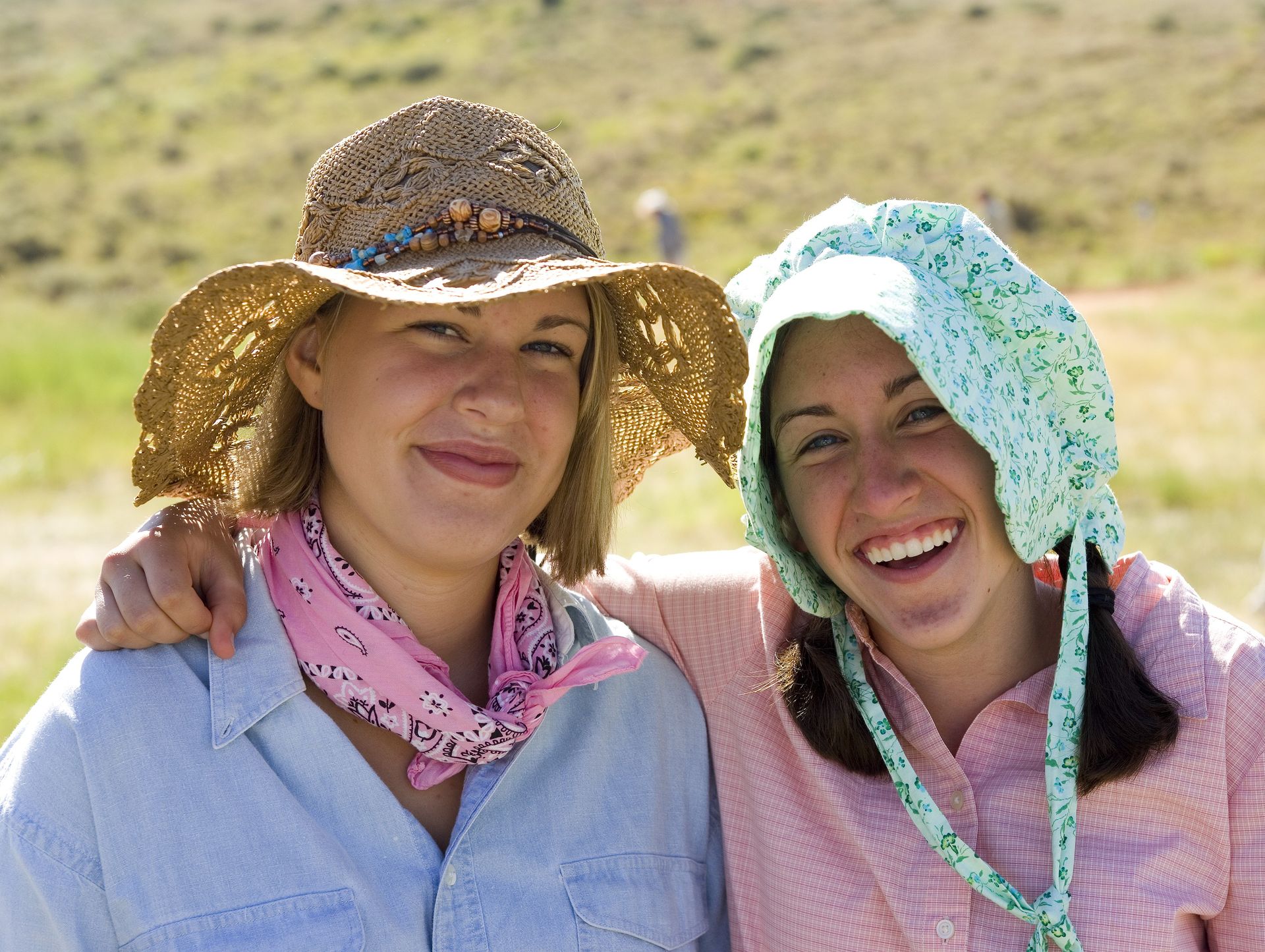 Two young women dressed as pioneers smile together while on trek.