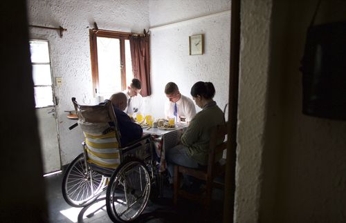 missionaries praying with Wilson and his daughter at the table