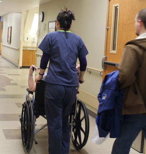 hospital employee pushing patient in wheelchair