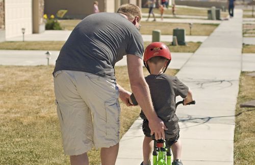 father helping son ride bicycle