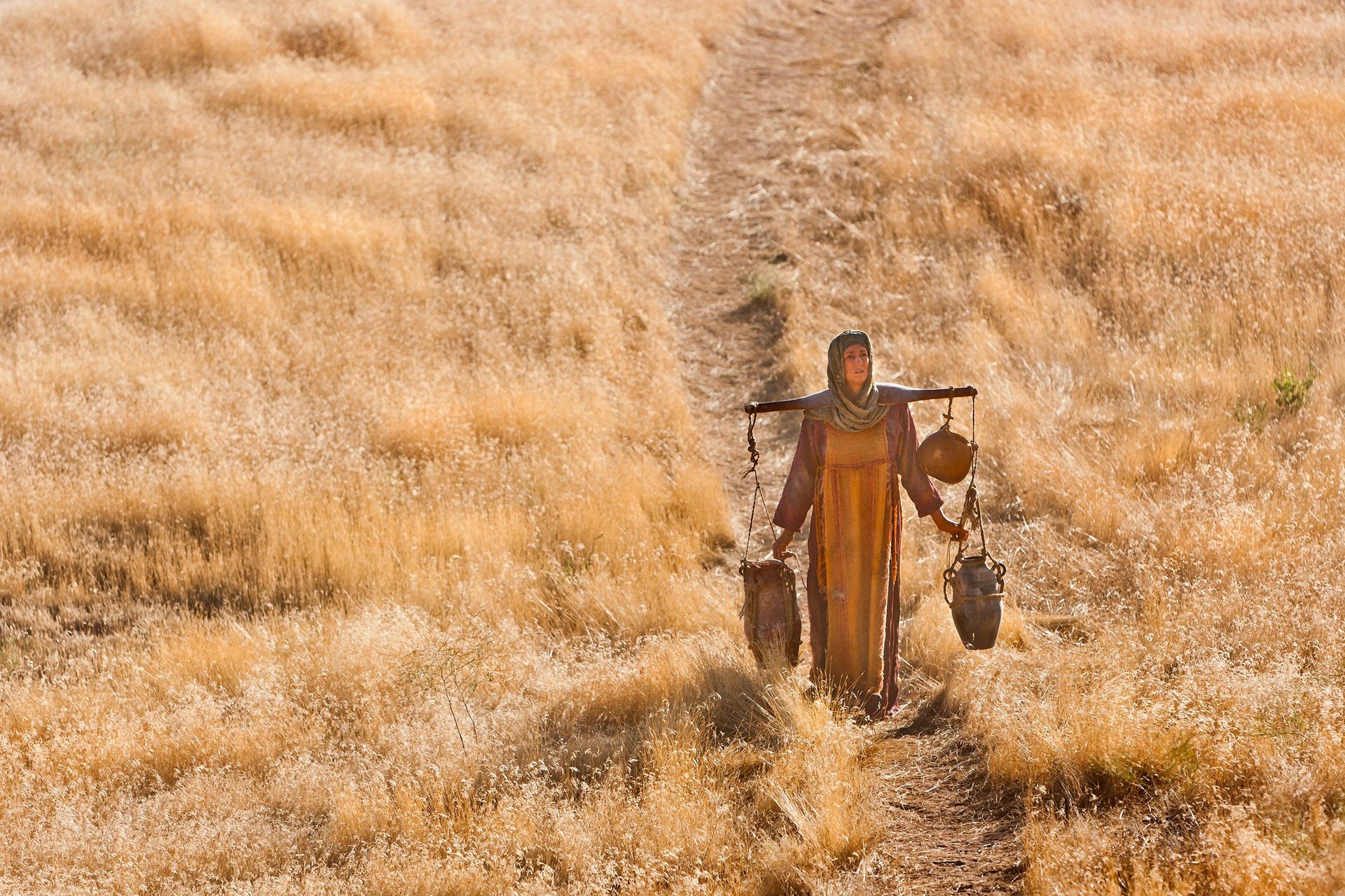 The Samaritan woman carries water from the well after learning from Jesus.