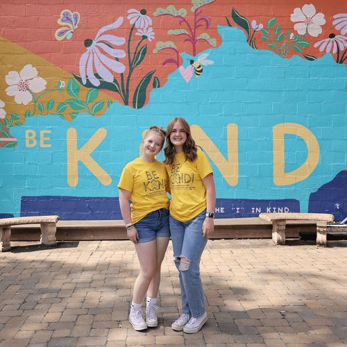 young women in front of a mural