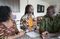 A Ghanaian family talks together. They are inside their home in their kitchen. They meet around a kitchen island. There are parents, youth, and younger siblings. It appears that two teenage daughters are leading a discussion. These are close-up images