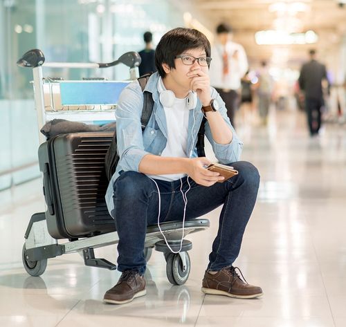 un hombre sentado sobre el equipaje en el aeropuerto