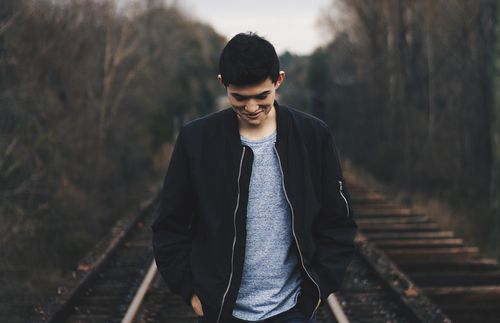 young adult walking on train tracks