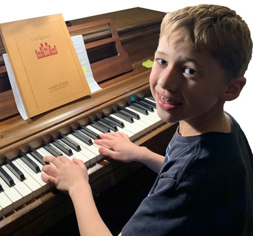 Brecken Tucker smiles as he practices the piano.