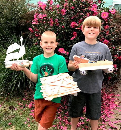 two brothers holding boats made from craft sticks