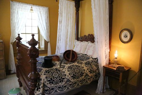 A bedroom with yellow walls and a large wooden bed inside the Brigham Young winter home.