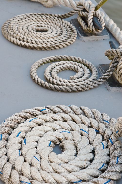 Three thick tan ropes coiled on a boat deck.