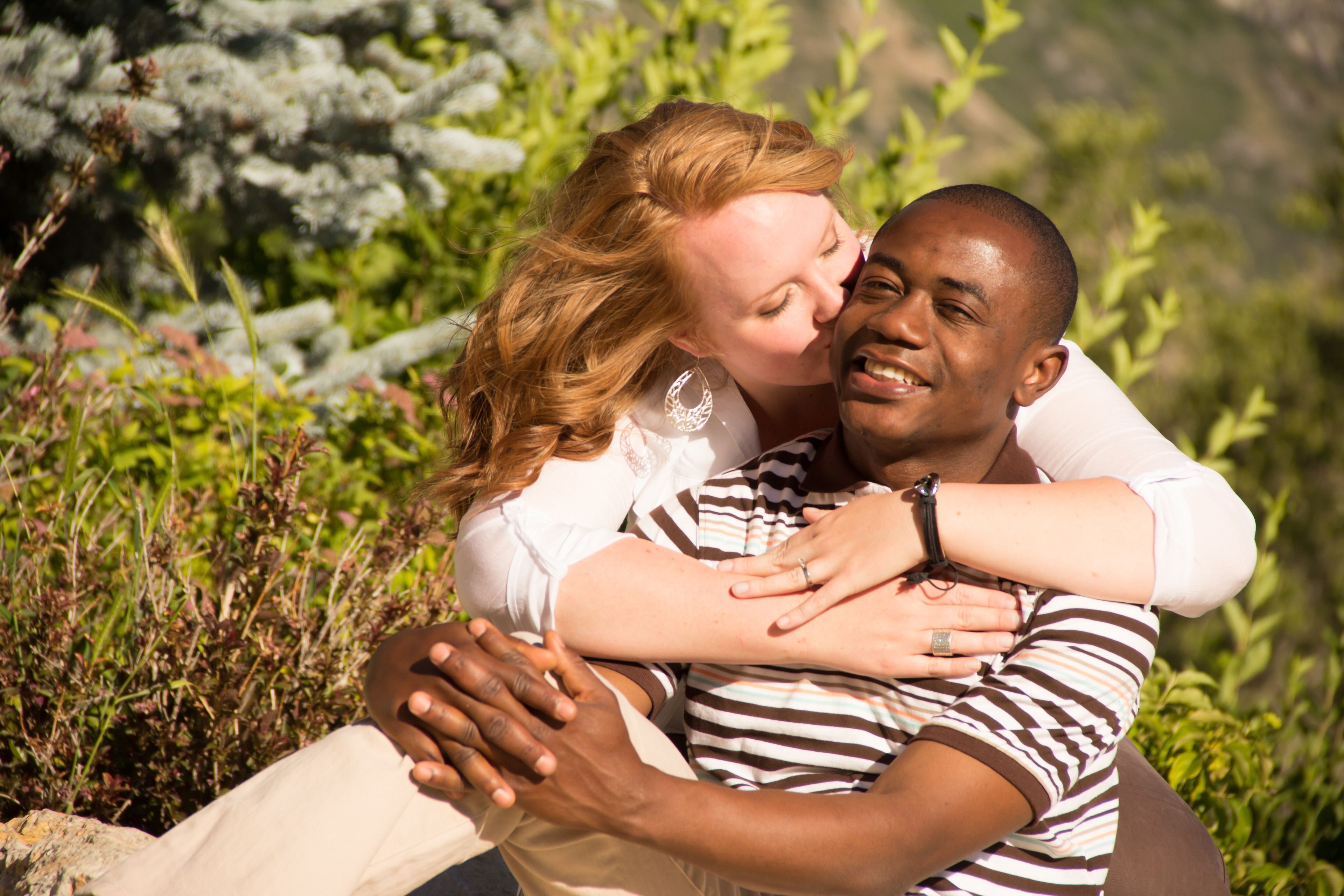 A woman kisses a man’s cheek in an engagement picture.