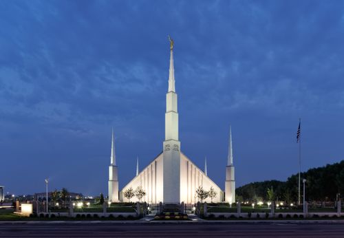 The Boise Idaho Temple as seen from across the street late in the evening after the lights have come on.