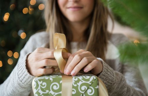 a woman wrapping a gift and smiling